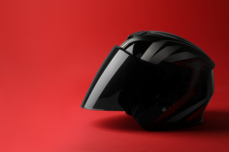 Modern motorcycle helmet with visor on red background, space for textの写真素材