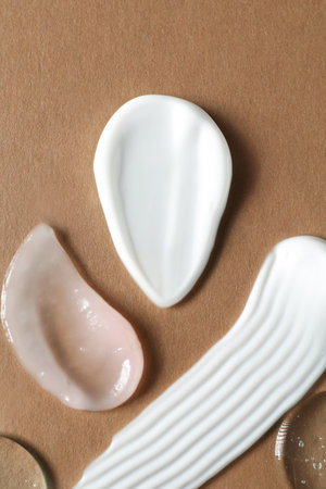Smears of different cosmetic products on brown background, flat layの写真素材