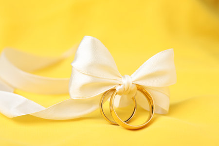 Wedding rings tied with ribbon on yellow cloth, closeupの写真素材