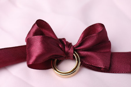Wedding rings tied with ribbon on pink cloth, closeupの写真素材