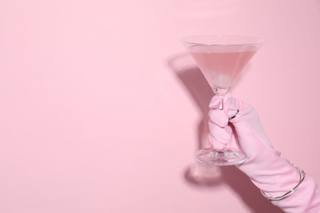 Woman holding glass of drink on pink background, closeup. Space for textの写真素材