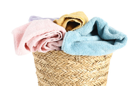 Laundry basket full of towels isolated on whiteの写真素材