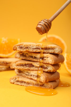 Pouring honey onto cookies on orange background, closeupの写真素材