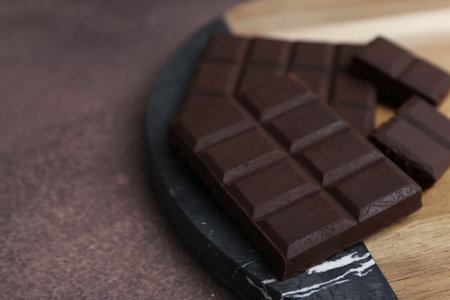 Pieces of delicious dark chocolate on brown table, closeup. Space for textの写真素材