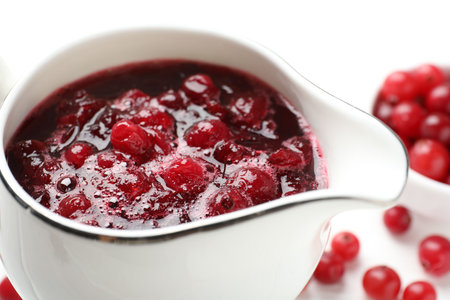 Tasty cranberry sauce in gravy boat and berries on table, closeupの写真素材