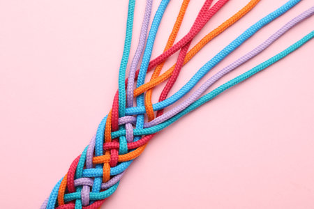 Braided colorful ropes on pink background, top view. Unity conceptの写真素材