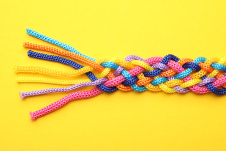 Braided colorful ropes on yellow background, top view. Unity conceptの写真素材