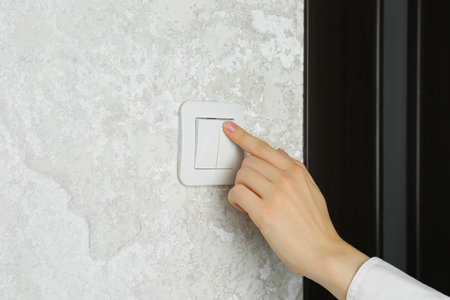 Woman turning light switch on, closeup view