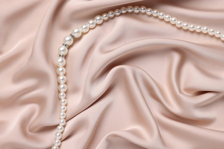 Elegant pearl necklace on beige fabric, top viewの写真素材