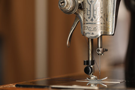 Vintage sewing machine with thread on blurred background, macro view. Space for text
