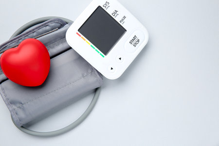 Blood pressure measuring device and squeeze heart on light gray background, top view. Space for textの写真素材