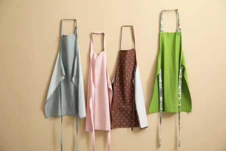 Many chef's aprons hanging on beige wallの写真素材