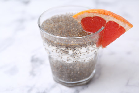 Glass of drink with chia seeds and grapefruit on white marble table, closeupの写真素材