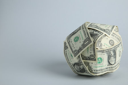 Ball made of dollars on light gray background. Space for text