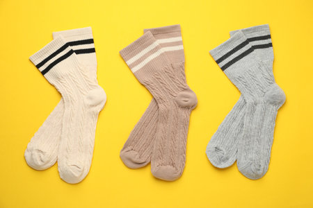 Different comfortable socks on yellow background, flat lay