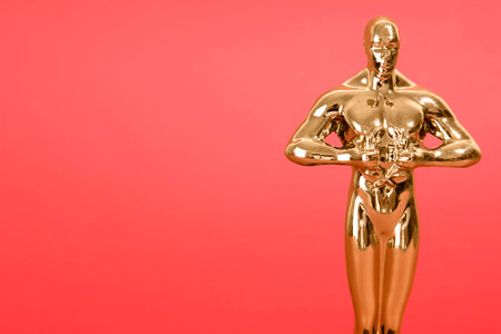 Golden trophy in shape of human figure on red background, closeup. Space for textの写真素材