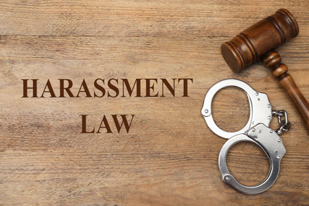 Harassment law. Judge's gavel and handcuffs on wooden table, flat layの写真素材