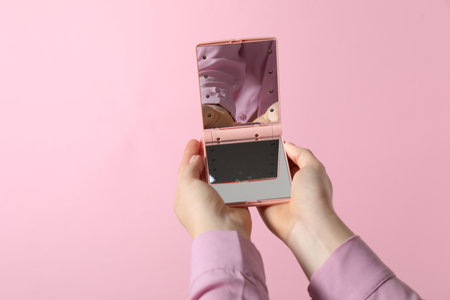 Woman holding pocket mirror on pink background, closeupの写真素材
