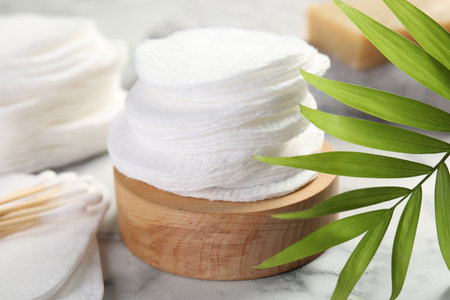 Cotton pads, swabs and palm leaf on light marble table, closeupの写真素材
