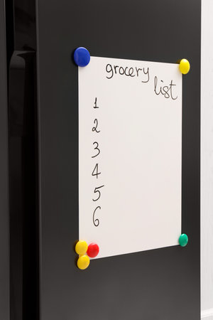 Magnetic board with grocery list on refrigerator in kitchenの写真素材