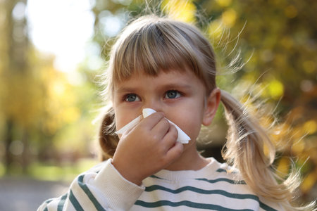 Little girl with runny nose in parkの写真素材