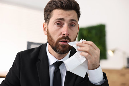 Sick man with runny nose in officeの写真素材
