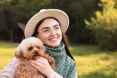 Smiling woman with cute dog in autumn park. Space for textの写真素材