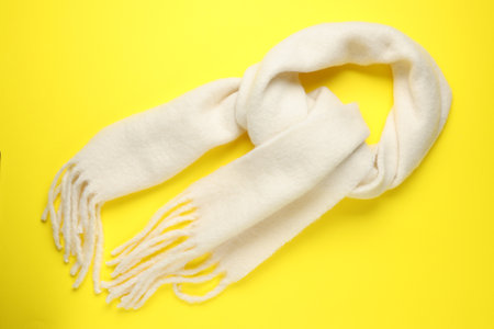 Warm woolen scarf on yellow background, top viewの写真素材