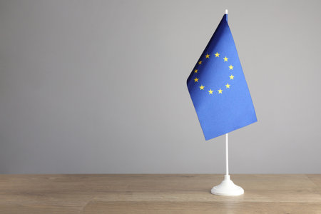 One flag of European Union on wooden table against gray background. Space for text