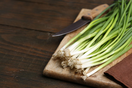 Fresh green onions and knife on wooden table, closeup. Space for textの写真素材