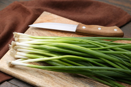 Fresh green onions and knife on wooden table, closeupの写真素材