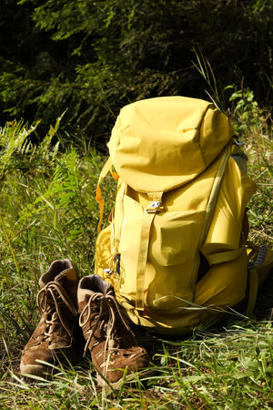 Backpack and trekking shoes on green grass outdoorsの写真素材