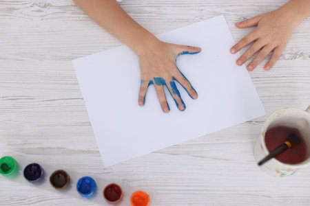 Boy drawing with palm at light wooden table, top viewの写真素材