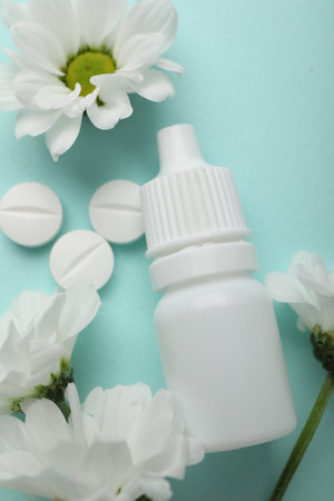 Allergy treatment. Nasal drops, pills and flowers on light blue background, flat layの写真素材