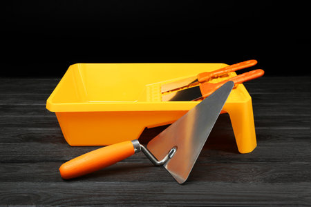Tray and putty knives on dark wooden table. Construction tools