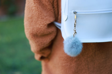 Woman with faux fur keychain on her backpack outdoors, closeup