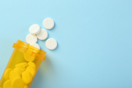 Bottle of antibiotic pills on light blue background, top view. Space for textの写真素材