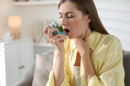 Young woman using asthma inhaler at homeの写真素材