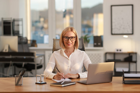 Portrait of smiling middle aged woman at table in officeの写真素材