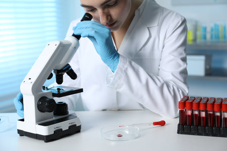 Laboratory testing. Doctor working with microscope at table indoorsの写真素材