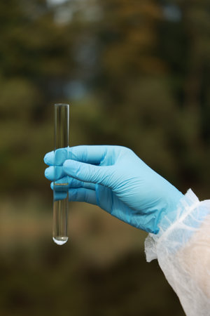 Examination of water quality. Researcher holding test tube with sample outdoors, closeupの写真素材