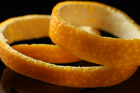 One fresh orange peel on black background, closeup