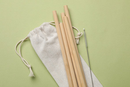 Bamboo drinking straws and cleaning brush on green background, top viewの写真素材