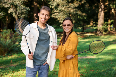 Young man and woman with badminton rackets and shuttlecock in parkの写真素材