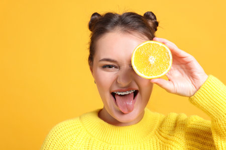 Person holding orange half near eye on orange background