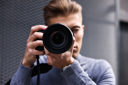 Professional photographer taking picture with camera outdoors, selective focus
