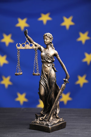 Figure of Lady Justice on gray table against European Union flagの写真素材