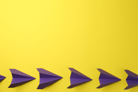 Handmade purple paper planes on yellow background, top view. Space for textの写真素材