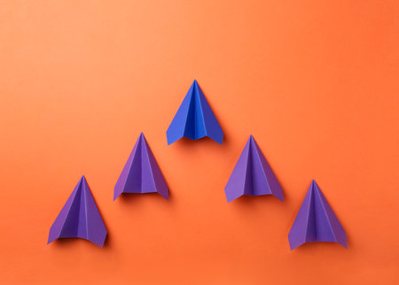 Handmade color paper planes on orange background, flat lay