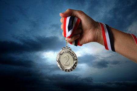 Woman holding silver medal in hand against sky, closeupの写真素材